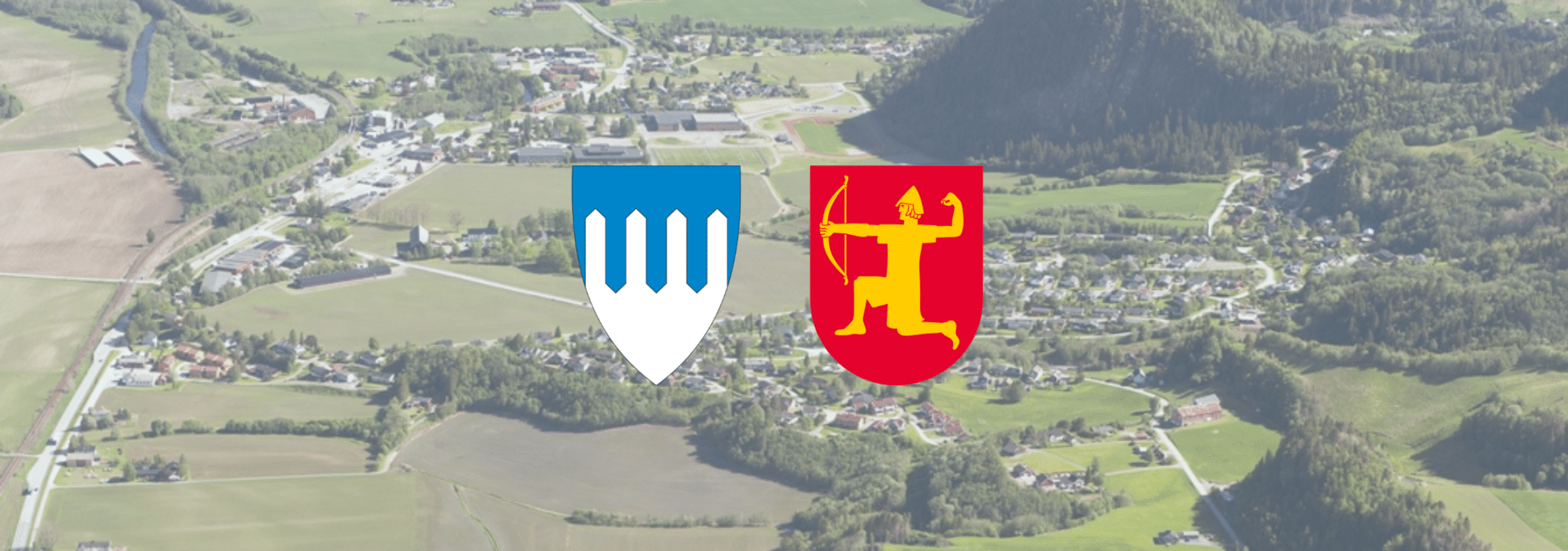 Flyfoto av et grønt jordbrukslandskap med jorder, elv, spredt bebyggelse og skogkledde åser. Midt på bildet er to kommune-/fylkesvåpen lagt over: ett blått og sølvfarget skjold med tre vertikale former, og ett rødt skjold med en gullfarget bueskytter.